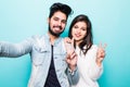 Indian young loving couple standing isolated over green wall background showing peace gesture Royalty Free Stock Photo