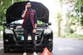 Indian young man with a silver car that broke down on the road.He has set up a warning triangle.He is waiting for the technician Royalty Free Stock Photo