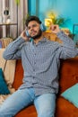 Indian young man in wireless headphones listening favorite energetic disco music at home sofa Royalty Free Stock Photo