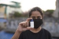 Indian young woman with corona preventive mask holding a medicine ampul on a rooftop in an afternoon in home isolation. Royalty Free Stock Photo