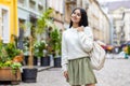 Indian young woman posing for camera, standing on city street with backpack and looking smiling Royalty Free Stock Photo