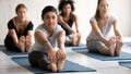 Indian woman practicing yoga at group lesson, Seated forward bend Royalty Free Stock Photo