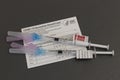 COVID-19 Vaccination booster syringes or hypodermic needles and Vaccination Record Card. COVID-19 boosters have been