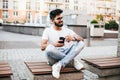 Indianhandsome man sitting with phone and smile on the street bench Royalty Free Stock Photo