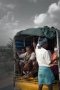 Indians riding in truck, guy standing on rear bumper