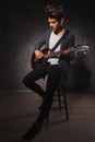 Indie artist playing guitar sitting on a chair in studio Royalty Free Stock Photo