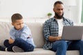 Indifferent Black Father Neglecting Son Using Laptop Sitting At Home