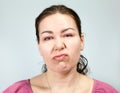 Indifferent, lazy facial expression in an adult woman, portrait on grey background, emotions series