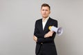 Indifferent young business man in classic black suit, shirt holding hands with megaphone folded isolated on grey