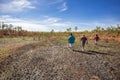 An indigenous Australian couple from the Kandiwal community accompanied by an Australian man walk through country burnt by
