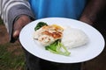 Indigenous Fijian man serve seafood and vegetables dish