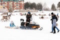 Indigenous people in national dress ride tourists on modern snowmobiles