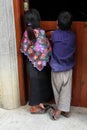 An indigenous Tzotzil Maya girl and boy in traditional dress looking into a house in Zinacantan, Mexico Royalty Free Stock Photo