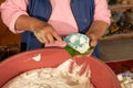 Indigenous woman preparing tamales with masa, stuffed with vegetables, covered by a corn leaf, traditional Mexican food