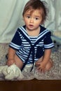 Indignant baby girl in the nautical striped vest sits