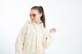 Indignant brunette girl in hoodie and red sunglasses looking at left side isolated over white background