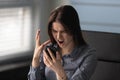 Indignant woman holding smartphone feels angry need repair broken gadget