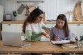 Indignant woman tutor with laptop helping teenage girl to prepare for school olympiad in mathematics