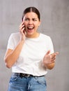 Indignant young woman talking on mobile phone
