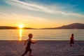 Indistinct small children running on beach at sunset.