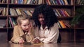 Lady tutor with curly hair teaches schoolgirl reading book