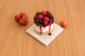 Individual cheesecake with all kinds of red berries and jam on a gray marble plate