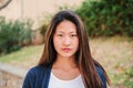 Individual close up portrait of serious young woman standing outdoors. One pensive teen female student looking at camera Royalty Free Stock Photo