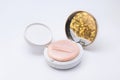 Compact case of foundation powder cushion with beige puff and shining golden reflection on white background Royalty Free Stock Photo