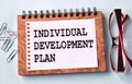 INDIVIDUAL DEVELOPMENT PLAN - words on a white sheet of paper on the background of a notebook, glasses and paper clips Royalty Free Stock Photo