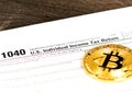 Individual income tax return 1040 form with metallic bitcoin coin