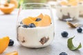 Individual layered desserts with sponge cake, cream and peach fruit, blueberry, trifle