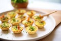 individual mini quiche lorraines on a platter with parsley