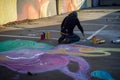 individual painting creative murals on the ground of an abandoned parking lot