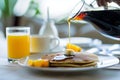 individual pouring syrup on pancakes, orange juice beside Royalty Free Stock Photo