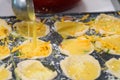 Individual quiches being made for breakfast, ladle pouring egg into filled pastry shells in muffin tin