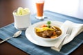 individual serving of beef stew, napkin and silverware beside