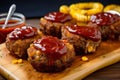 Individual servings of mini meatloaf topped with tangy BBQ sauce, served with crispy onion rings and sweet corn