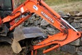 Kubota brand personal excavator parked next to stone wall