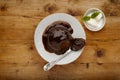 An individual sticky toffee sponge cake, with a sticky toffee sauce, on a white plate with a spoon, and a small bowl of ice cream Royalty Free Stock Photo