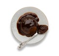 An individual sticky toffee sponge cake, with a sticky toffee sauce, on a white plate with a spoon, isolated on white Royalty Free Stock Photo