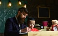 Individual studying concept. Busy kid studying at school. Father checking homework, helps to boy, son. Teacher in formal Royalty Free Stock Photo