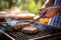 individual using a wide spatula flipping a burger on grill outdoors Royalty Free Stock Photo