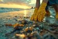 Individual in yellow gloves cleans beach, protecting water resources