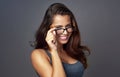 Individuality is so sexy. Studio portrait of an attractive young woman peering over her glasses against a grey Royalty Free Stock Photo