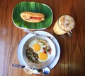 Indochina pan-fried egg with toppings with Baguette bread sandwich with cheese, ham on fresh Green banana leaf and ice coffee Royalty Free Stock Photo