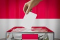 Indonesia flag, hand dropping ballot card into a box - voting, election concept