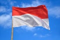 Indonesias red and white flag flying against blue sky Royalty Free Stock Photo