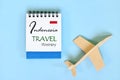 Indonesia travel plan or itinerary written on blue notepad with flag and wooden airplane. Tour guide and outline.