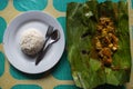Indonesian dish PEPES IKAN on banana leaf on plate plus rice