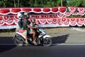 Indonesian family riding on a scooter against Indonesia national flags in Bali Indonesia